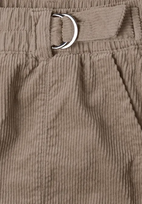Gros plan d’un pantalon en velours côtelé beige, taille élastique avec poche et boucle en D.