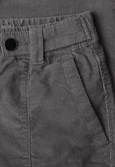 Nahaufnahme einer grauen Cordhose mit seitlicher Tasche und erhabener Rippstruktur.