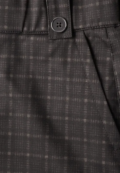 Close-up van donker geruite broek met knoop en zak