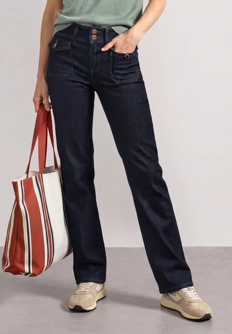 Dunkle Jeans, beige Sneaker, Streifen-Shopper und grünes T-Shirt – lässiges Alltagsoutfit.