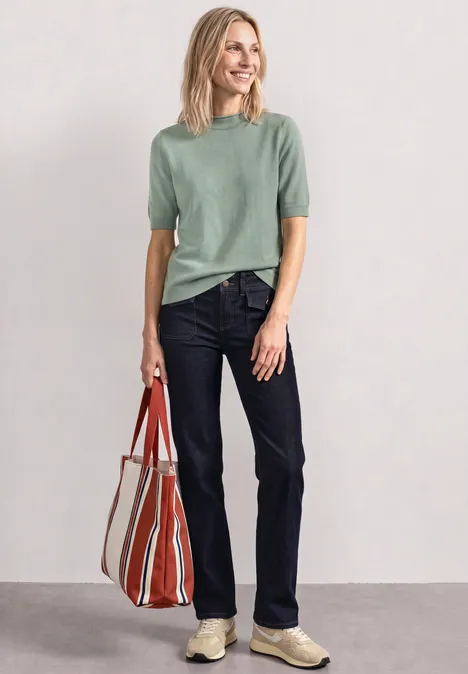 Frau mit grünem Shirt, Jeans und gestreifter Tasche