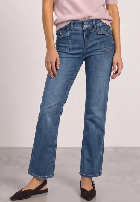 Mid Waist Straight Leg Jeans im Casual Fit Mid Blue Washed Frau in blauen, gerade geschnittenen Jeans und schwarzen Ballerinas, nur Unterkörper sichtbar.