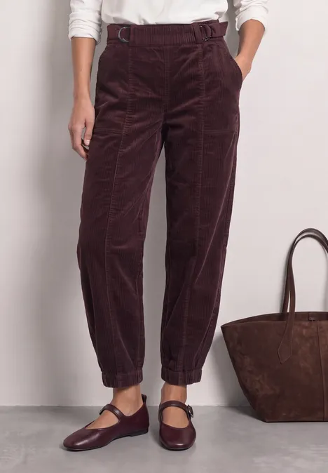 High Waist Barrel Leg Hose mit Elastikbund vintage ruby Dunkelrote Cordhose mit hohem Bund, lockerer Passform und elastischen Umschlagsäumen, kombiniert mit Mary-Jane-Schuhen.