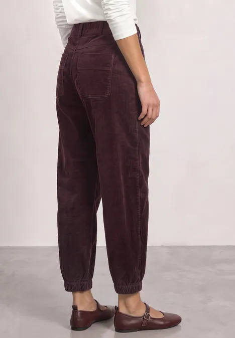 High Waist Barrel Leg Hose mit Elastikbund vintage ruby Rückenansicht einer Person mit bordeauxroter Cordhose, elastischen Bündchen und braunen Loafers.