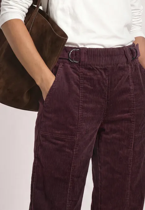High Waist Barrel Leg Hose mit Elastikbund vintage ruby Eine Person trägt hochgeschnittene weite Cordhosen in Burgund mit weißem Oberteil und brauner Wildledertasche.