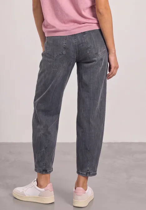 High Waist Barrel Leg Jeans im Loose Fit Steel Grey Wash Rückansicht einer Person in lockeren grauen Jeans, rosa Oberteil und weißen Sneakers vor neutralem Hintergrund.