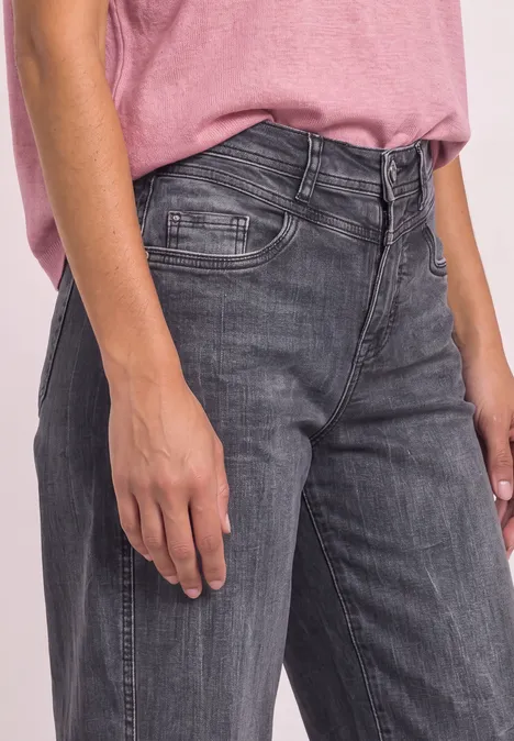 High Waist Barrel Leg Jeans im Loose Fit Steel Grey Wash Person mit rosa T-Shirt und grauen Jeans, zu sehen von Taille bis Oberschenkel.