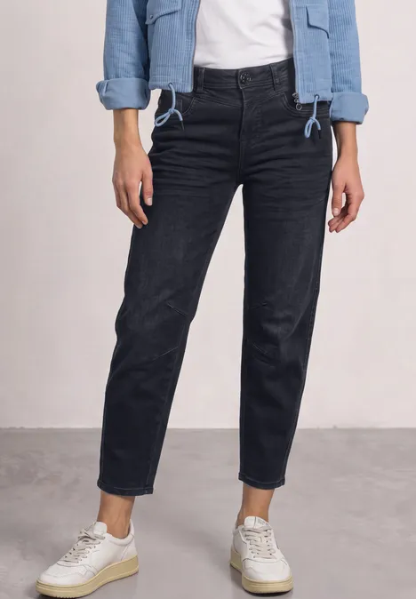 High Waist Barrel Leg Jeans im Loose Fit blue black soft wash Eine Person trägt schwarze Jeans, weiße Sneaker und eine hellblaue Jeansjacke vor schlichtem Hintergrund.