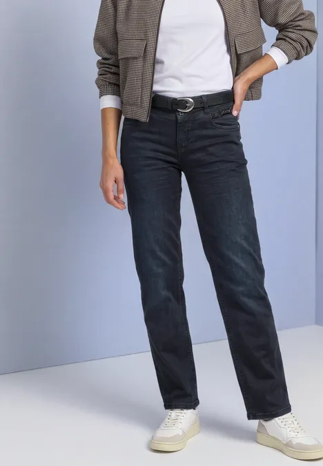 Mid Waist Straight leg Jeans im Casual Fit blue black soft wash Eine Person trägt gerade geschnittene dunkelblaue Jeans, weiße Sneaker, schwarzen Gürtel und helles Hemd.