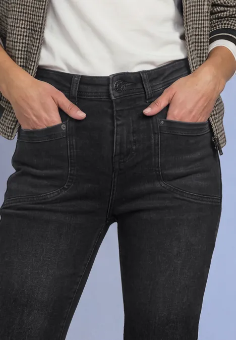 Jean bootcut taille haute, coupe slim Black Washed Vorderansicht einer Person mit schwarzen Jeans und kariertem Blazer, Hände in den Taschen.