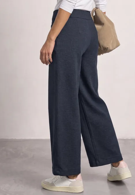 Wide Leg Hose mit aufgesetzten Taschen darkest blue mel. Frau trägt hochgeschnittene, weite dunkelblaue Hose mit weißen Sneakern und Beuteltasche.