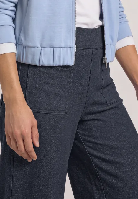 Wide Leg Hose mit aufgesetzten Taschen darkest blue mel. Eine Person trägt dunkelblaue, hochgeschnittene Hose mit seitlichen Taschen und hellblauem Oberteil.