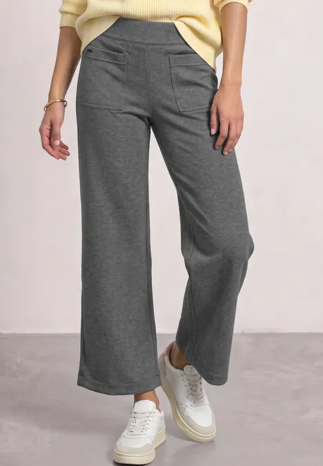 Graue, weite Hose mit hohem Bund und weißen Sneakern, lässig kombiniert.