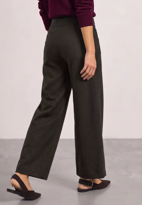 Wijde donkergrijze broek met zijzakken, zwarte ballerina’s met bandje, rood truitje, zijaanzicht.
