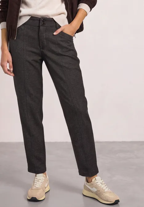 Donkergrijze, rechte broek in wolmix, gecombineerd met beige sneakers.