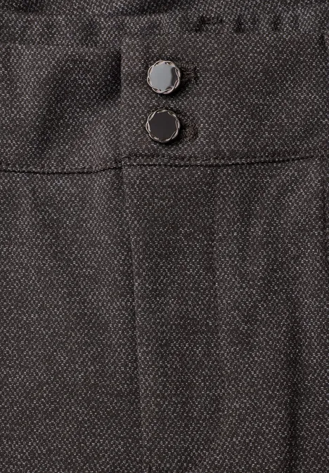 Close-up van een donkere stoffen broek met twee zichtbare knopen in de taille.