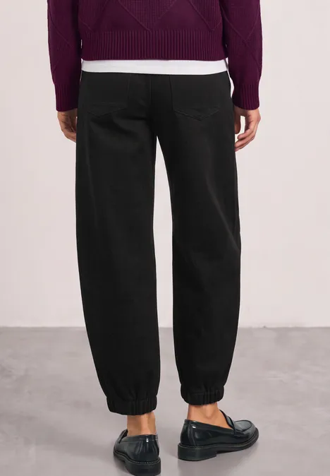 Pantalon taille haute Barrel Leg, coupe décontractée Black Rückansicht einer Person mit schwarzen, hinten gerafften Hosenbeinen und schwarzen Loafers.