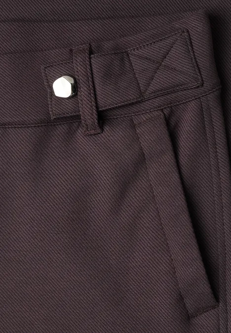 Nahaufnahme einer braunen Hose mit Bund, Gürtelschlaufe, Eingrifftasche und silbernem Knopf.