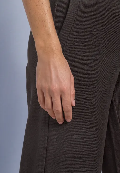 Hand en onderarm van een persoon zijaanzicht, donkere kleding op de achtergrond.