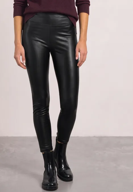 Schlanke Person trägt schwarze Lederleggings und schwarze Ankle-Boots.