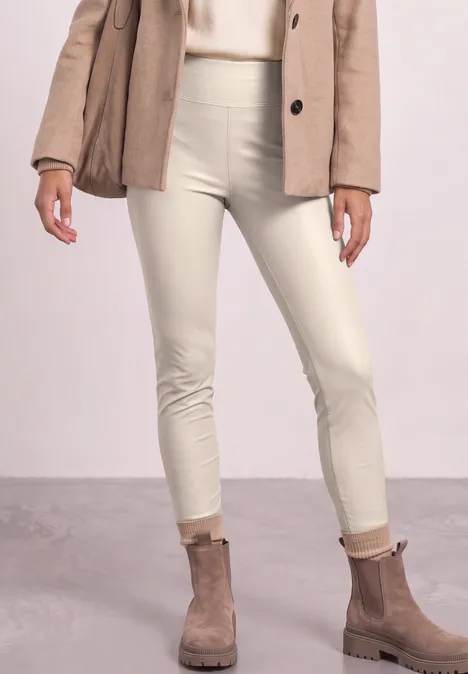 Frau trägt cremefarbene Skinny-Hose, beige Stiefeletten und einen hellbraunen Blazer.