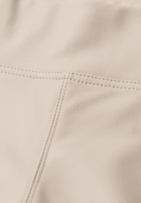 Nahaufnahme einer beigen Leder- oder Kunstlederoberfläche mit sichtbaren Nähten