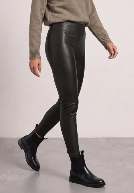 Leggings in Leder-Optik black coffee Schwarze Lederleggings und schwarze Chelsea-Boots im Studio-Setting, kombiniert mit beigem Pullover.
