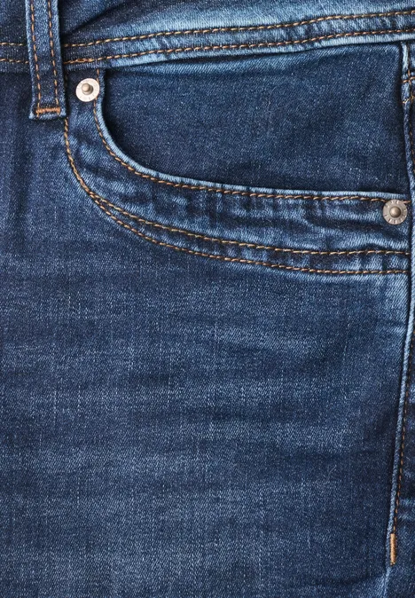 Nahaufnahme einer blauen Jeans mit sichtbarer Tasche, Naht und silberfarbenen Nieten.