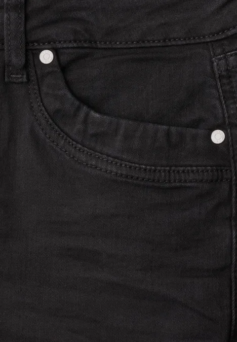 Nahaufnahme einer schwarzen Jeans mit sichtbarer Tasche und Metallnieten.