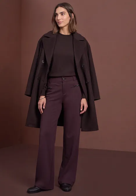 Mid Waist broek met rechte pijpen in casual pasvorm berry plum Frau trägt elegante, dunkle Kleidung: bordeauxfarbene Hose, schwarzes Top und Mantel lässig über den Schultern.