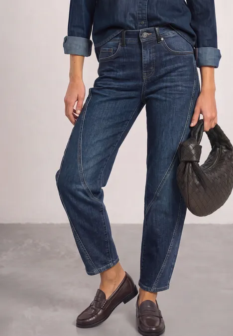 Relaxed Barrel Leg Jeans im Loose Fit Dark blue authentic washed Frau trägt dunkelblaue, gerade geschnittene Jeans, Hemd in Navy und Loafers, dazu schwarze Tasche.