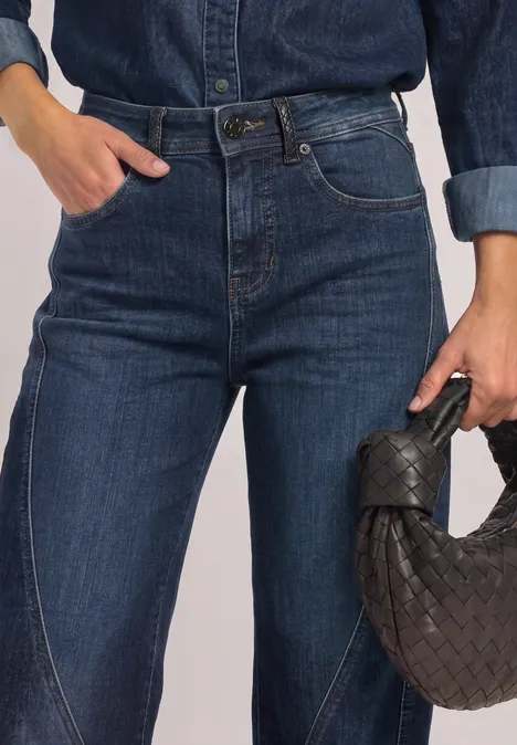 Relaxed Barrel Leg Jeans im Loose Fit Dark blue authentic washed Frau trägt dunkelblaue High-Waist-Jeans und hält eine geflochtene Handtasche.