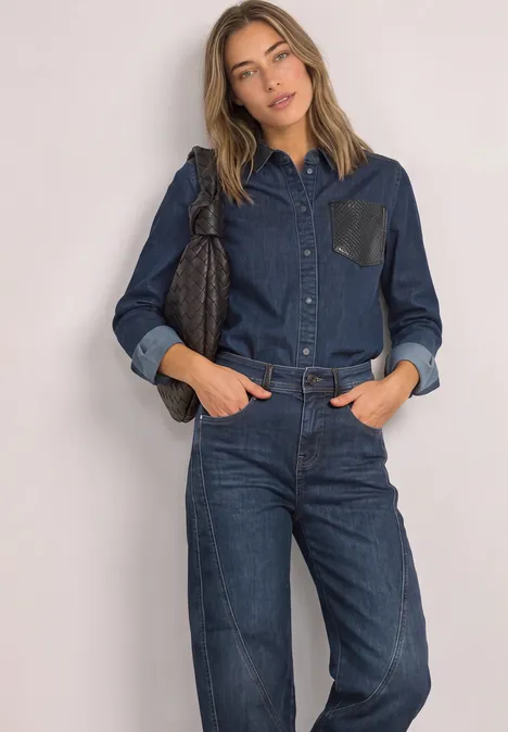 Relaxed Barrel Leg Jeans im Loose Fit Dark blue authentic washed Junge Frau in dunkelblauem Denim-Hemd und Jeans posiert mit Tasche vor neutralem Hintergrund.