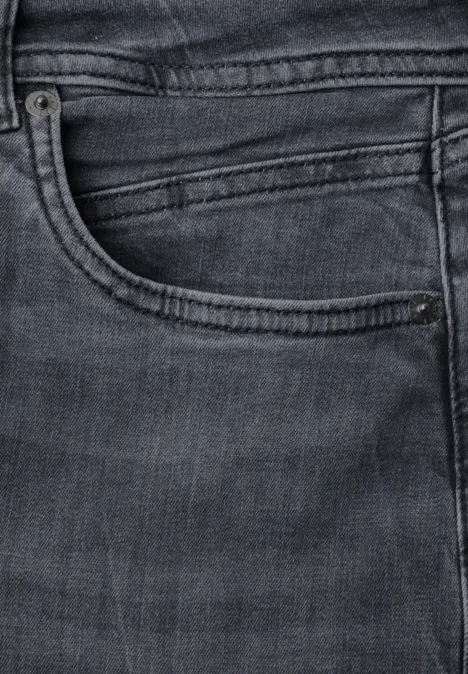 Gros plan sur la poche avant d'un jean foncé avec coutures et poche à ticket.