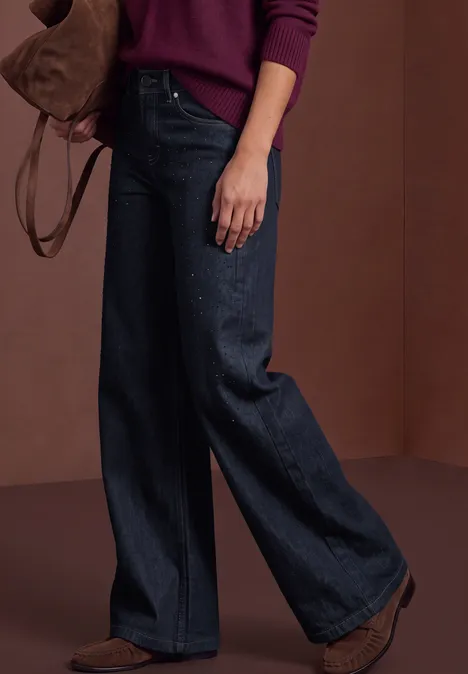 Jeans met High Waist en Wide Leg pijpen in een Loose Fit pasvorm Rinse Washed Frau trägt breite, dunkle Jeans mit braunen Stiefeln und einem Schulterbeutel, kombiniert mit einem kastanienroten Pullover.