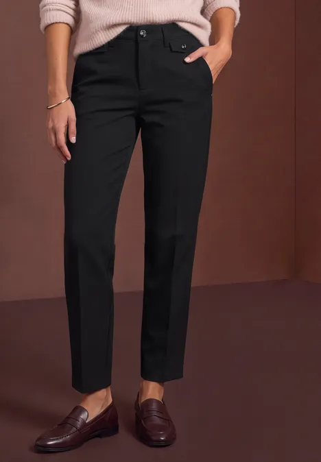 Pantalon noir droit arrivant à la cheville, associé à des mocassins marron.