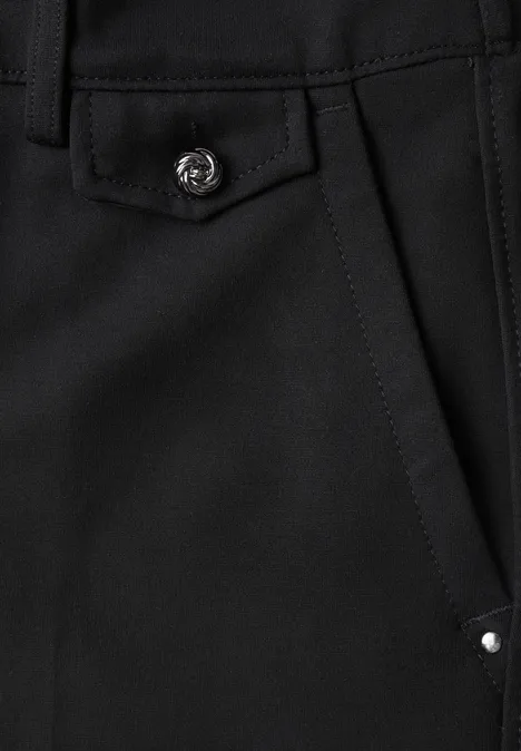 Gros plan d'une poche noire avec rabat, bouton-pression argenté et petite rivure.