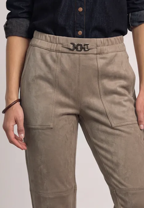 Personne porte un pantalon beige taille haute avec ceinture marquée et poches latérales.