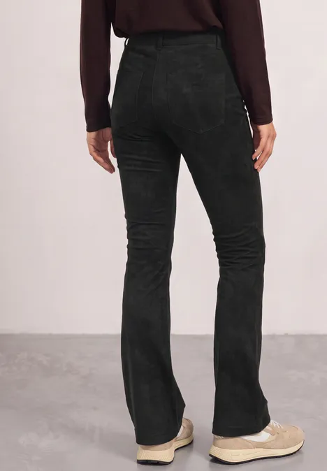 High Waist Bootcut Hose im Slim Fit Black Rückansicht einer Person in schwarzen Cordflared-Hosen und beigen Sneakers vor schlichtem Hintergrund.