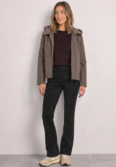 High Waist Bootcut Hose im Slim Fit Black Frau trägt braunen Hoodie, dunkelrotes Shirt, schwarze Jeans und helle Sneaker vor hellem Hintergrund.