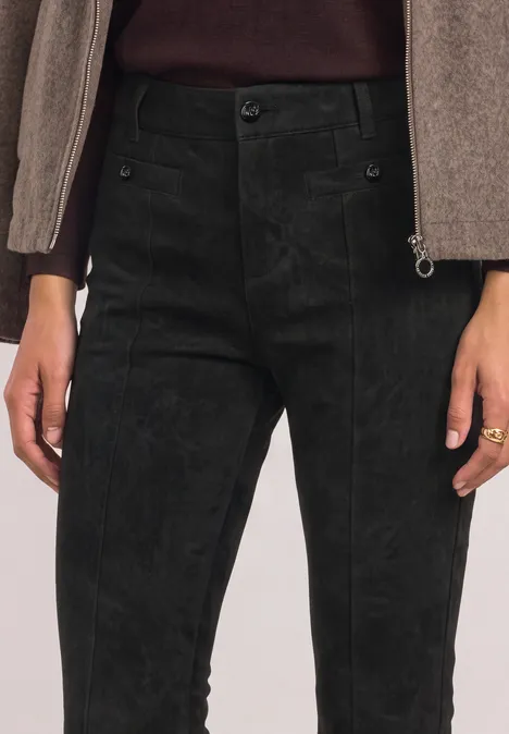 High Waist Bootcut Hose im Slim Fit Black Schwarze Cordhose auf Taillenhöhe, kombiniert mit beigem Oberteil und Ring am Finger.