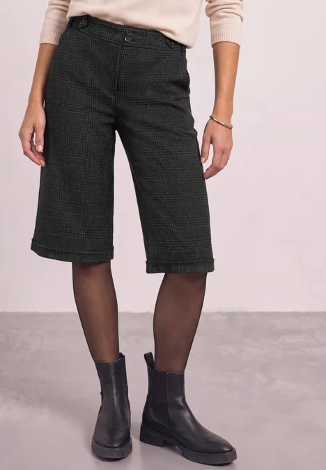 Bermuda met High Waist en Wide Leg pijpen in casual pasvorm Black Person trägt schwarze Bermudashorts, feine Strumpfhosen und schwarze Stiefeletten vor hellem Hintergrund.