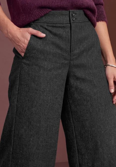 Bermuda met High Waist en Wide Leg pijpen in casual pasvorm Black Detailaufnahme einer Person in grauen, weiter geschnittenen Stoffhosen mit Hand in Hosentasche