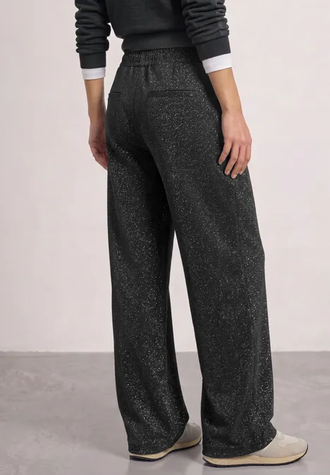 Broek met High Waist en Wide Leg pijpen in een Loose Fit pasvorm Black Foto einer von hinten gezeigten Person in dunkelgrauen, weiten Lounge-Hose mit Glitzereffekt und Hausschuhen.