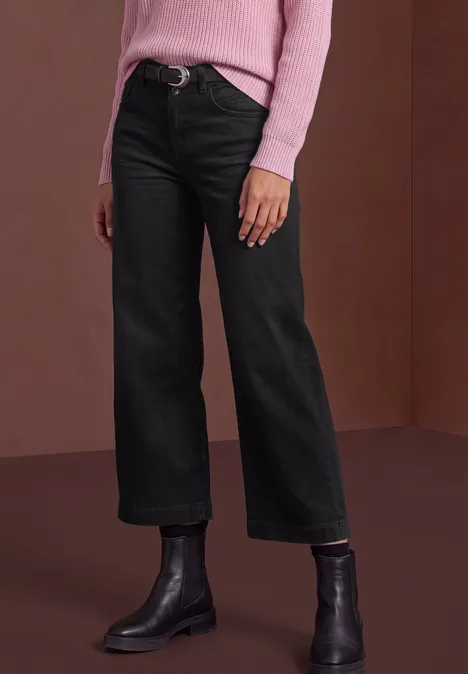 Mid Waist Jeans Culotte im Loose Fit black authentic washed Person trägt schwarze, gerade geschnittene Jeans, schwarze Stiefeletten und einen rosafarbenen Pullover.