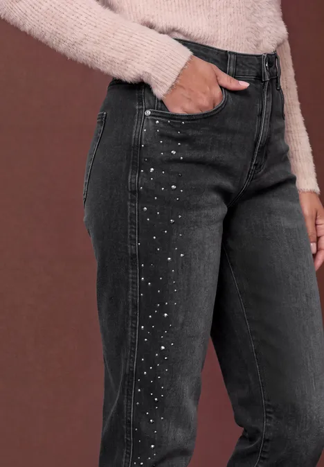 High Waist Barrel Leg Jeans im Loose Fit grey washed Schwarze Jeans mit seitlichen Strassstein-Details, kombiniert mit einem beigen Strickpullover.