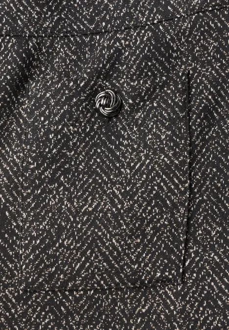 Gros plan sur un manteau en tissu gris foncé à chevrons avec un bouton.