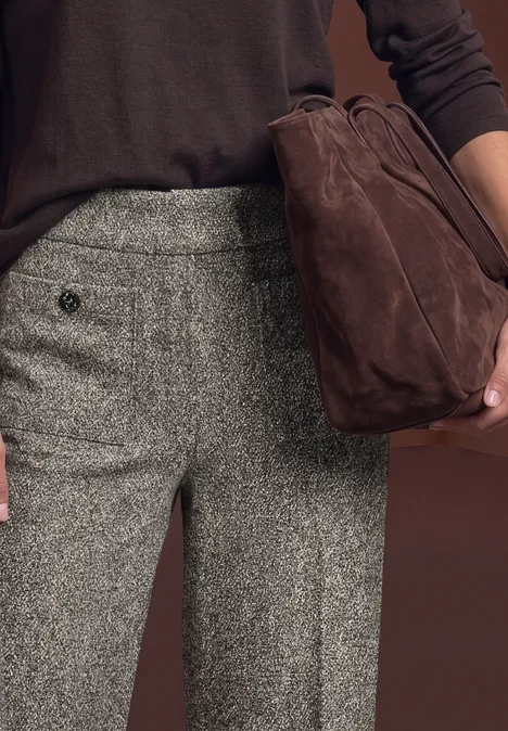 Pantalon taille haute à jambes larges, coupe décontractée bark brown Hose aus grauem Tweed und dunkelbrauner Pullover, dazu eine braune Wildledertasche in der Hand.