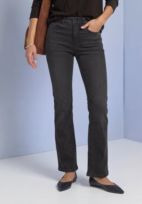 Bootcut-jeans met Mid Waist-taille in Slim Fit Black Washed Schwarze gerade geschnittene Jeans und schwarze spitze Ballerinas, Hand in Tasche.