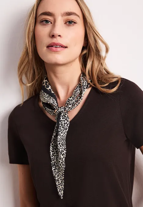 Frau in schwarzem T-Shirt und gemustertem Halstuch, lässig gestylt.